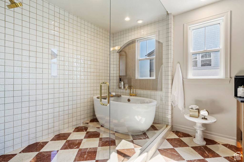 Full bath featuring baseboards, tiled shower, a freestanding tub, tile walls, and recessed lighting