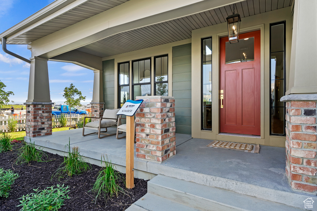 Doorway to property featuring covered porch and brick siding