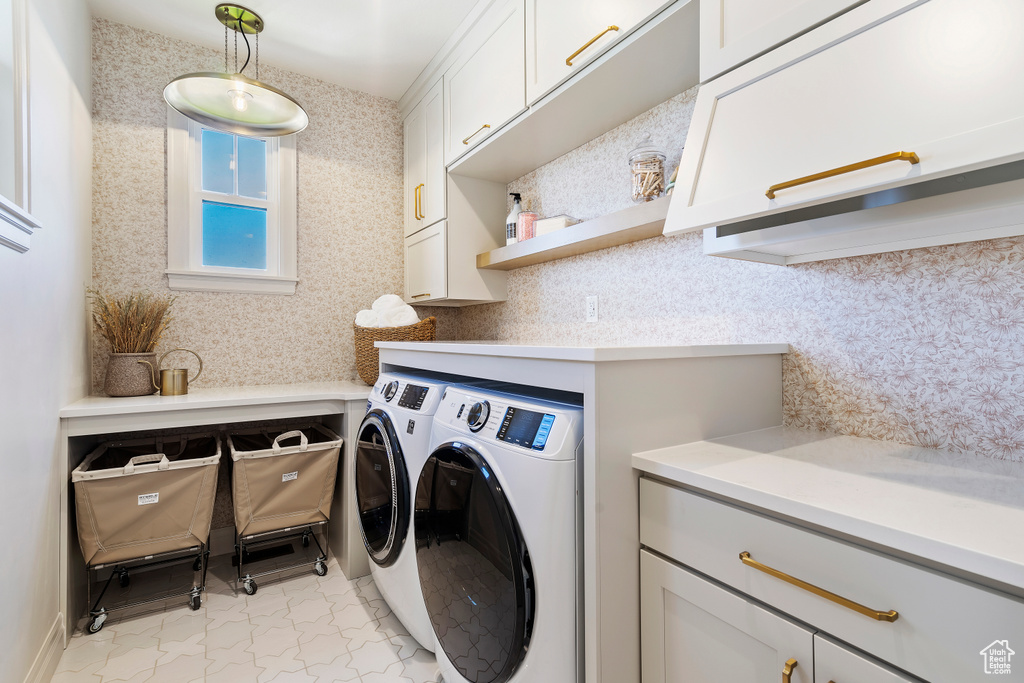 Washroom with marble finish floor, cabinet space, washing machine and clothes dryer, and wallpapered walls