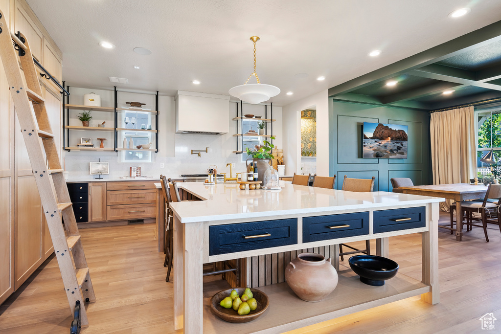 Kitchen with a kitchen island with sink, light countertops, light wood-style flooring, and open shelves