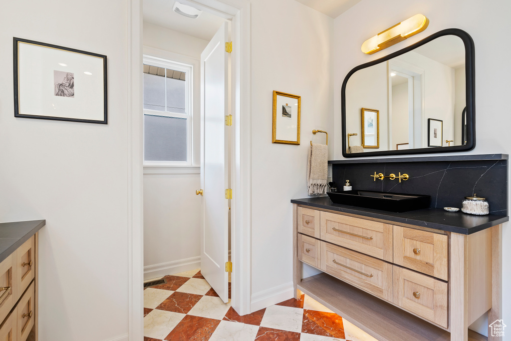 Bathroom with backsplash, vanity, baseboards, and tile patterned floors
