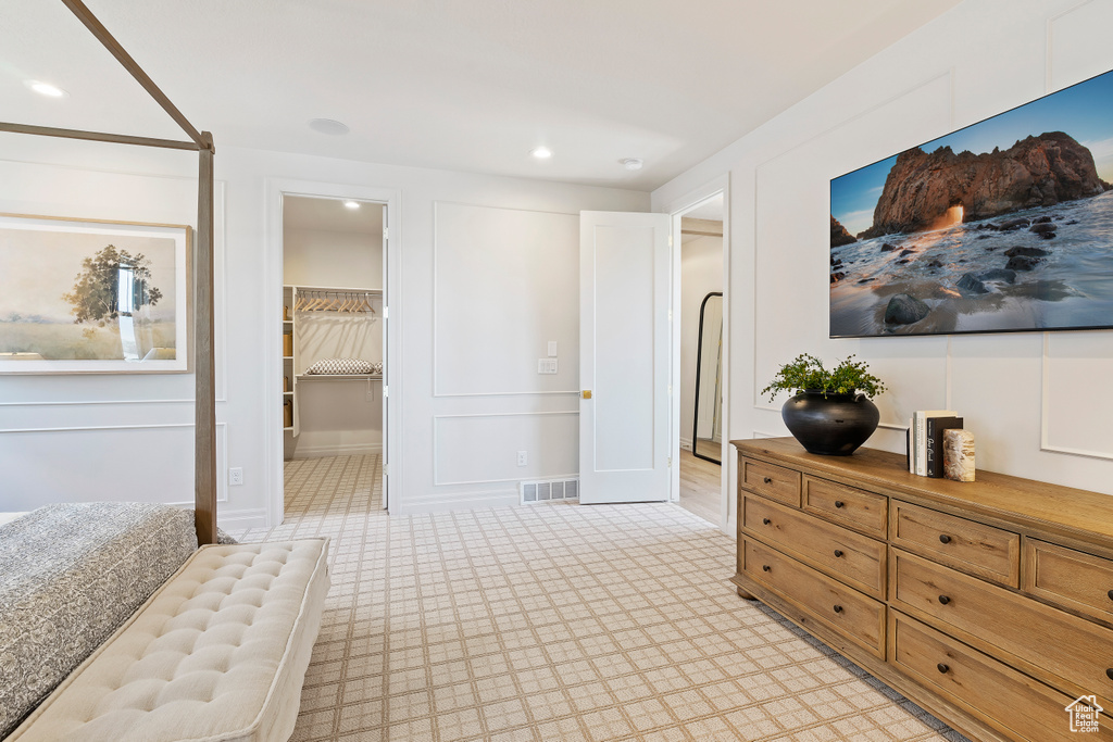 Bedroom with a walk in closet, visible vents, a decorative wall, and recessed lighting