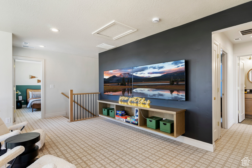 Recreation room with a textured ceiling, visible vents, attic access, and baseboards