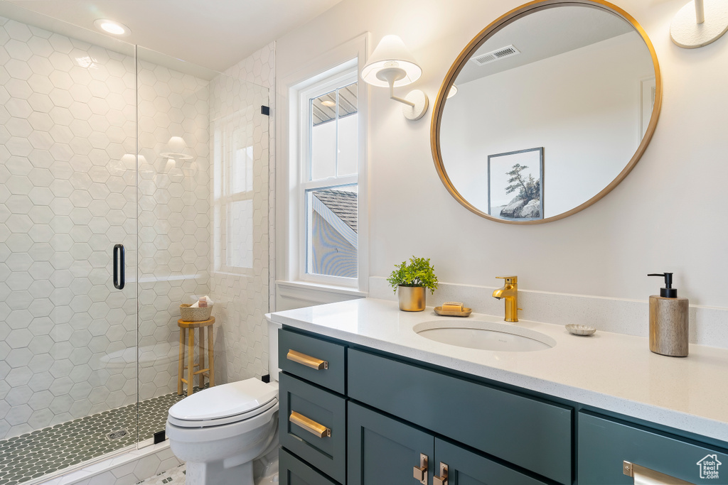 Bathroom with toilet, a stall shower, vanity, and visible vents