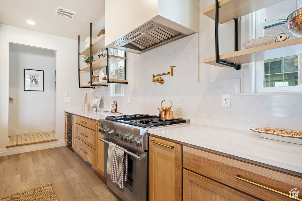 Kitchen with premium range hood, visible vents, open shelves, and high end stainless steel range