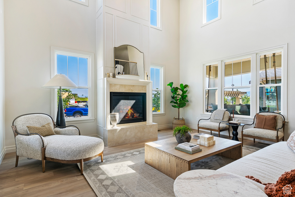 Living area featuring light wood finished floors, a glass covered fireplace, a high ceiling, and baseboards
