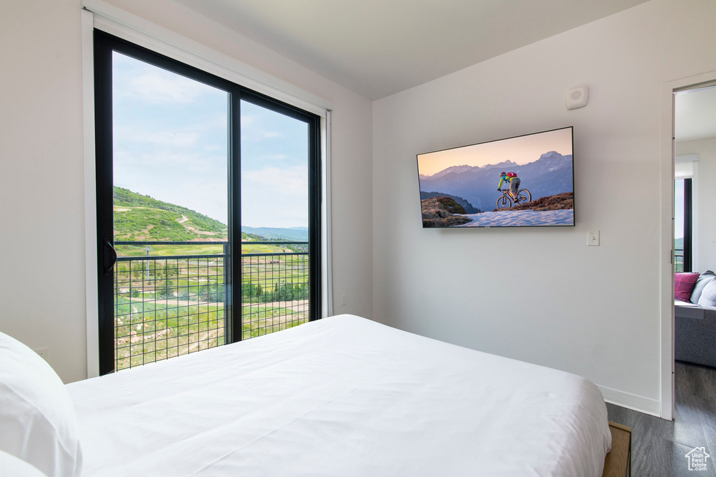 Bedroom with wood finished floors, a mountain view, and baseboards