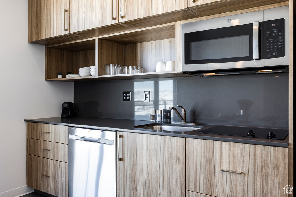 Kitchen with appliances with stainless steel finishes, modern cabinets, a sink, and light brown cabinets