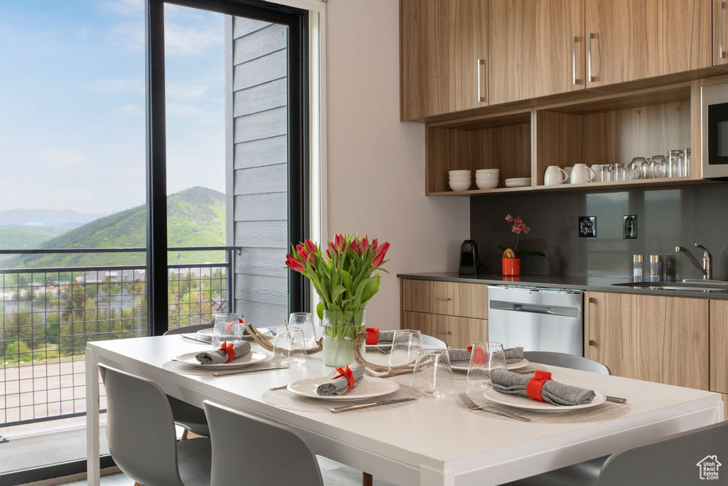 Kitchen featuring modern cabinets, a sink, stainless steel appliances, a mountain view, and light brown cabinetry