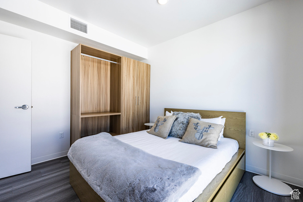 Bedroom with dark wood finished floors and baseboards