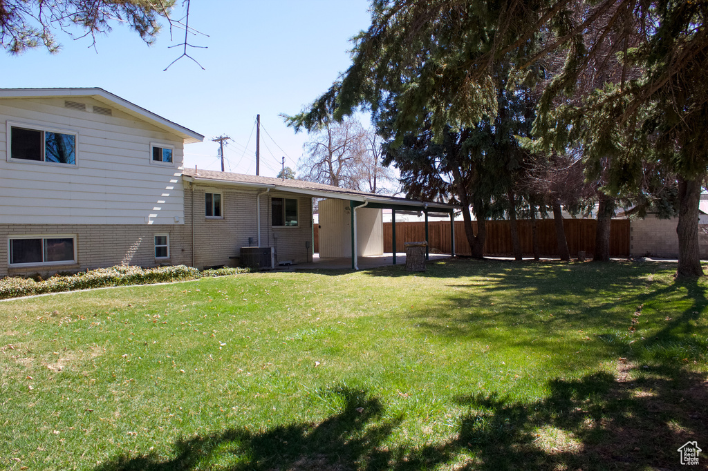 View of yard featuring a carport, fence, and central AC