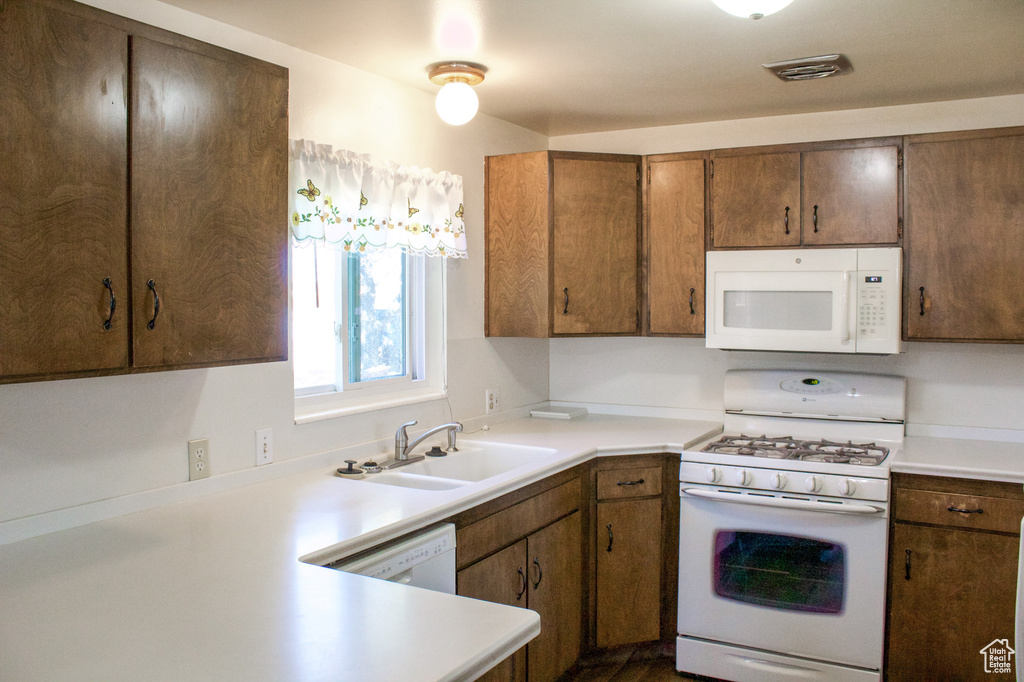 Kitchen featuring light countertops, a sink, visible vents, and white appliances