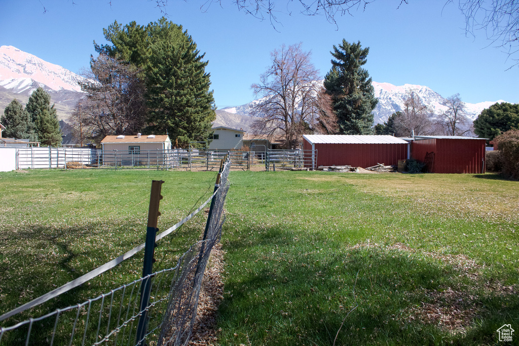 View of yard featuring an outbuilding, fence, a mountain view, and a pole building