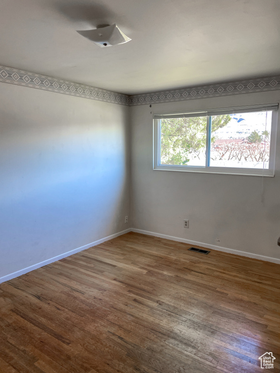Unfurnished room with baseboards, visible vents, and wood finished floors