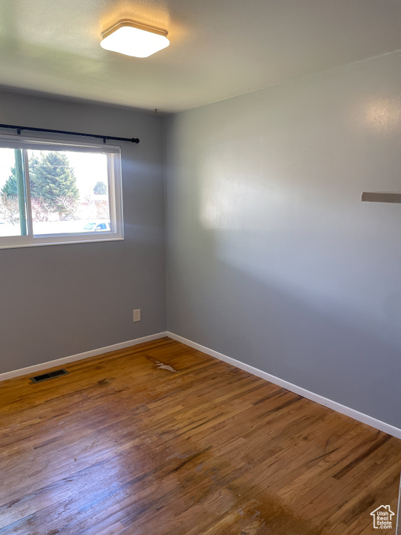 Empty room with wood finished floors, baseboards, and visible vents