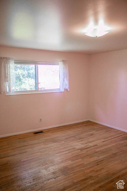 Unfurnished room with baseboards, visible vents, and wood finished floors