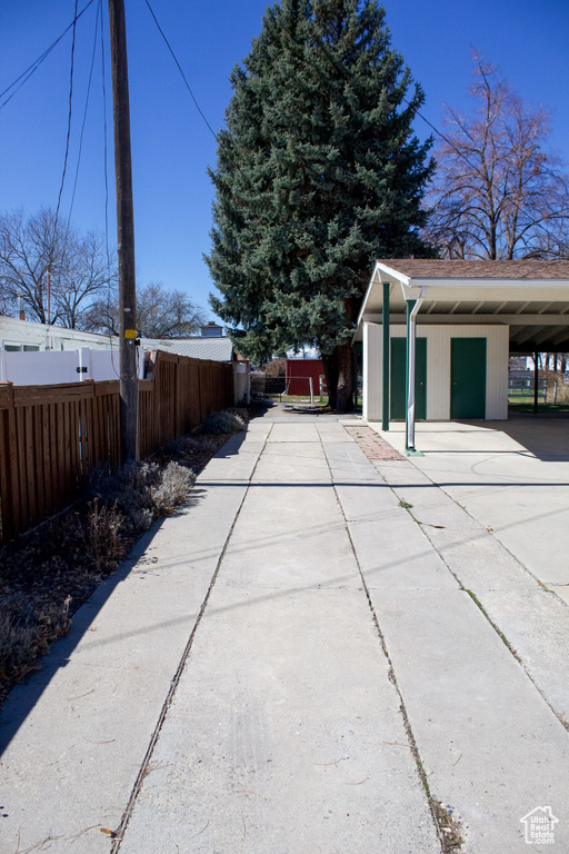 Exterior space with an outdoor structure, fence, concrete driveway, and a carport