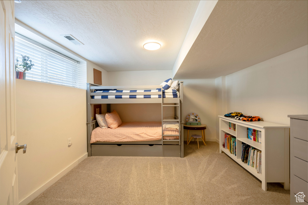 Bedroom featuring carpet floors, baseboards, visible vents, and a textured ceiling
