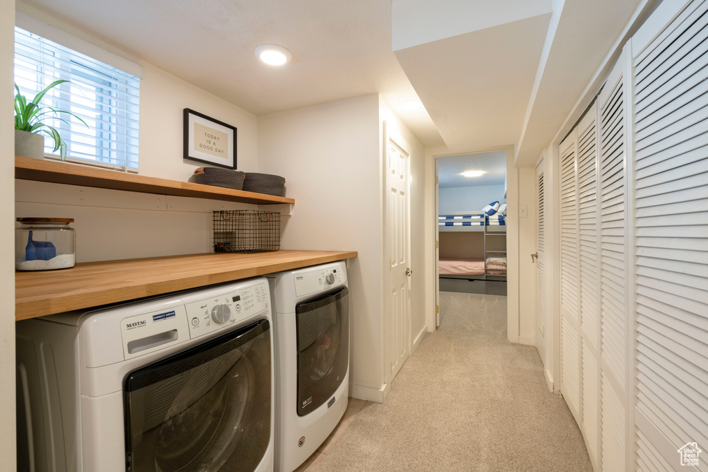 Washroom with laundry area, separate washer and dryer, and light carpet