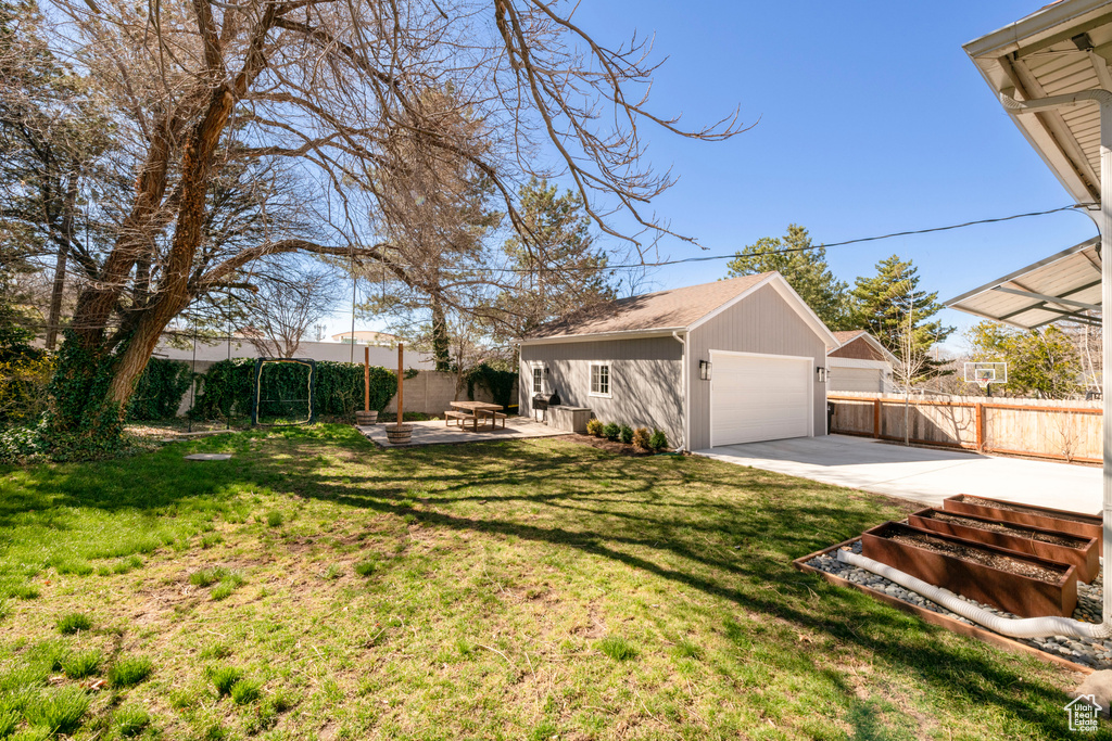 View of yard featuring a fenced backyard, an outbuilding, a garage, and a patio