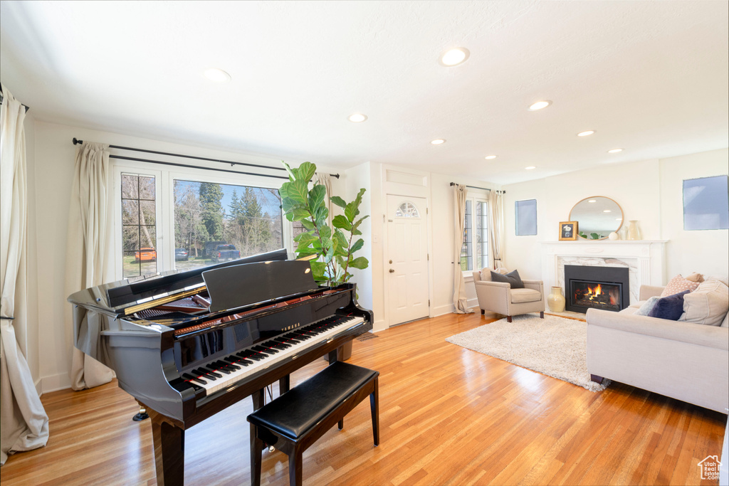 Living room with a wealth of natural light, recessed lighting, a premium fireplace, and light wood finished floors