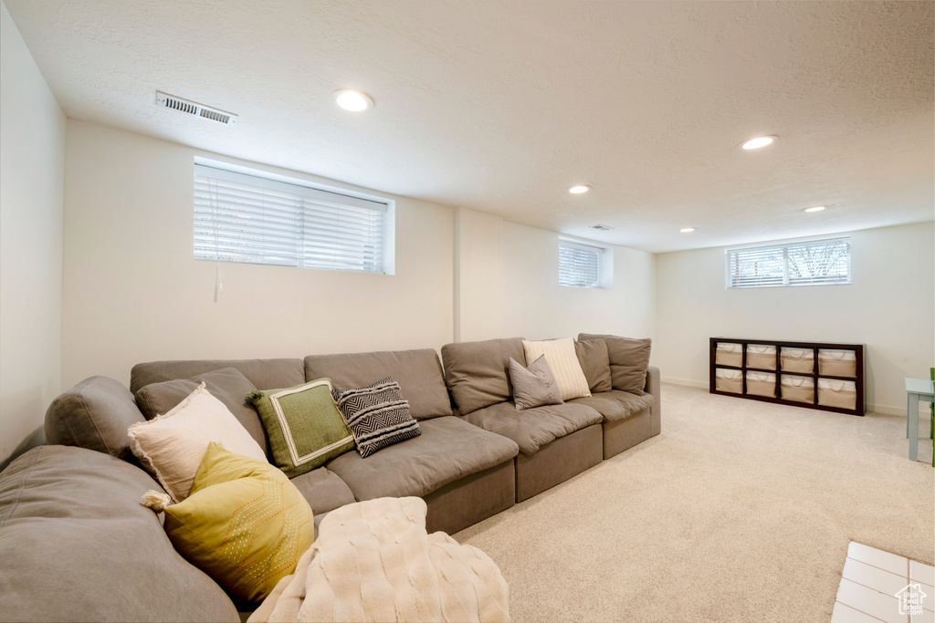 Living area featuring recessed lighting, baseboards, a textured ceiling, visible vents, and light carpet