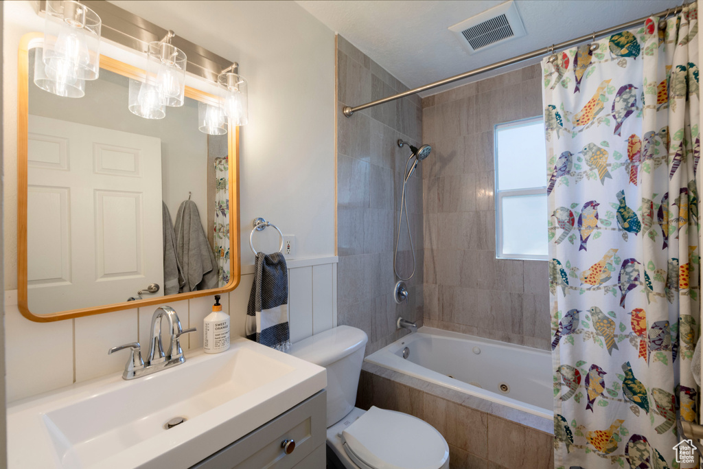 Bathroom with visible vents, tiled shower / bath, toilet, and vanity