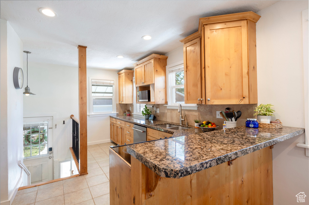 Kitchen featuring tasteful backsplash, light brown cabinetry, a sink, dishwasher, and a peninsula
