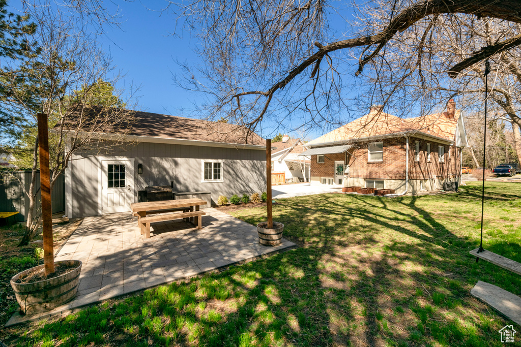 Back of house with a patio area, brick siding, and a yard
