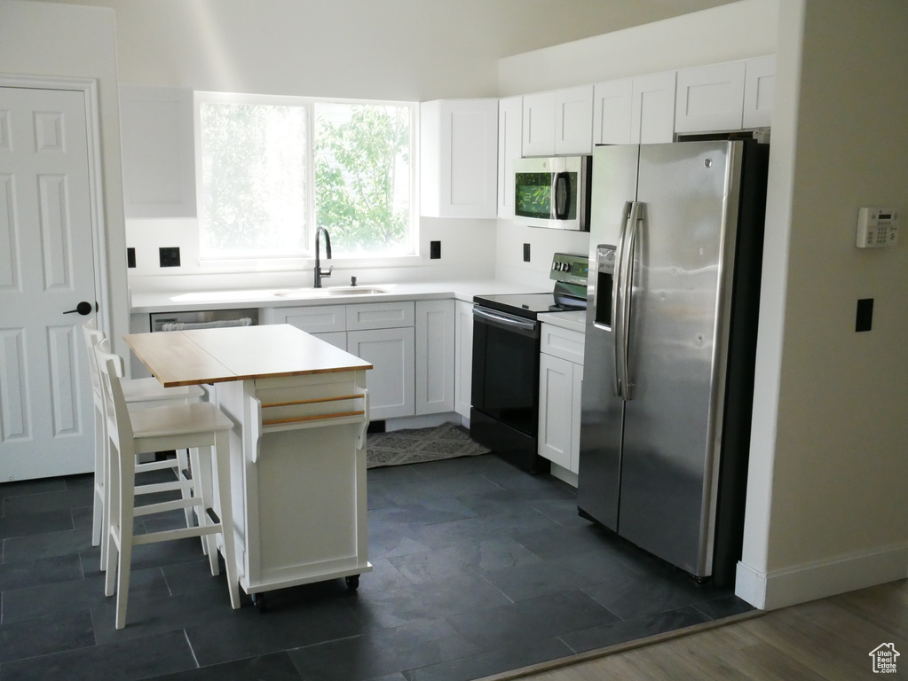 Kitchen featuring appliances with stainless steel finishes, a sink, and white cabinetry