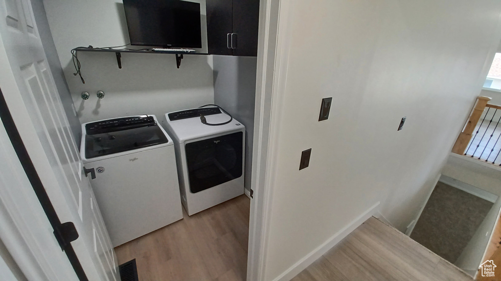 Laundry area with washing machine and clothes dryer and light wood-style floors