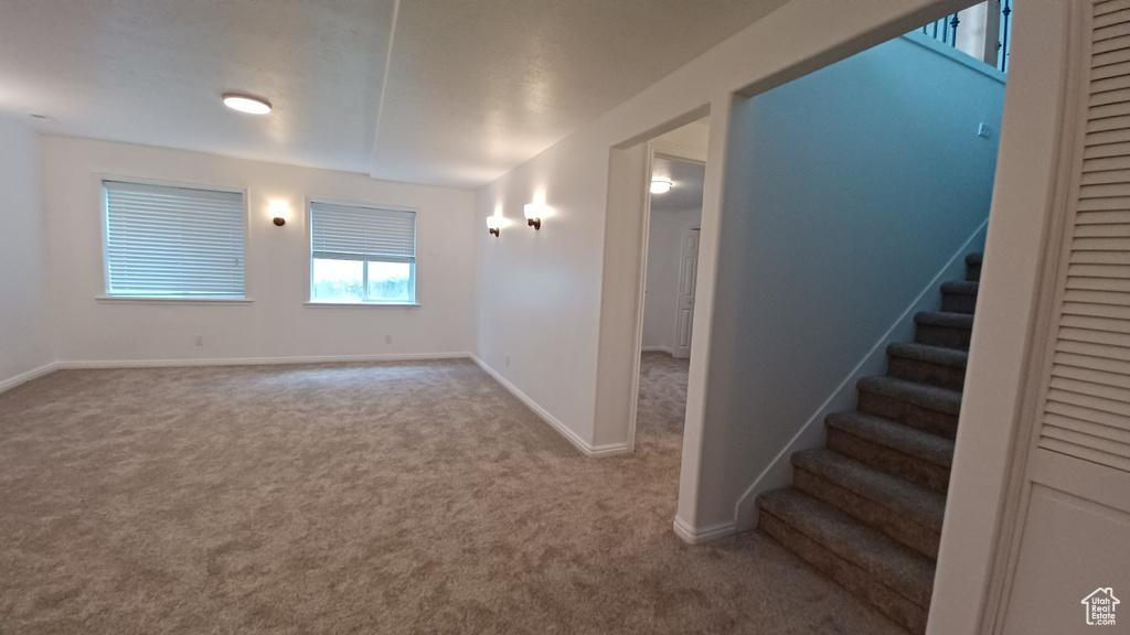 Spare room featuring carpet, stairway, and baseboards