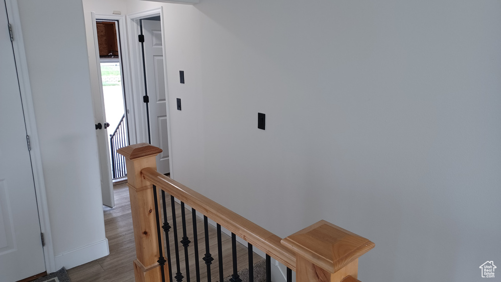 Corridor featuring an upstairs landing, baseboards, and wood finished floors