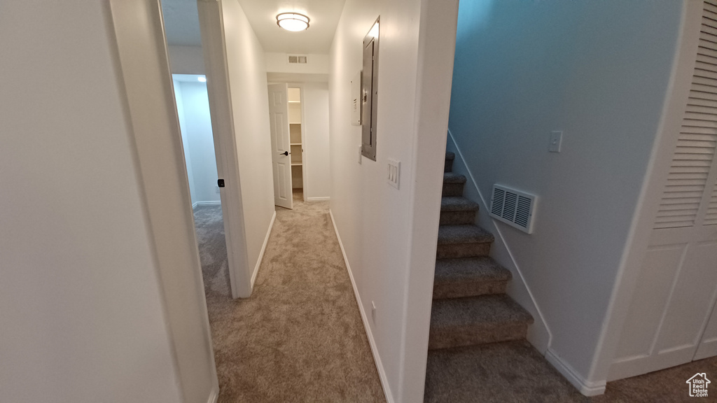 Hall featuring carpet flooring, stairs, baseboards, and electric panel