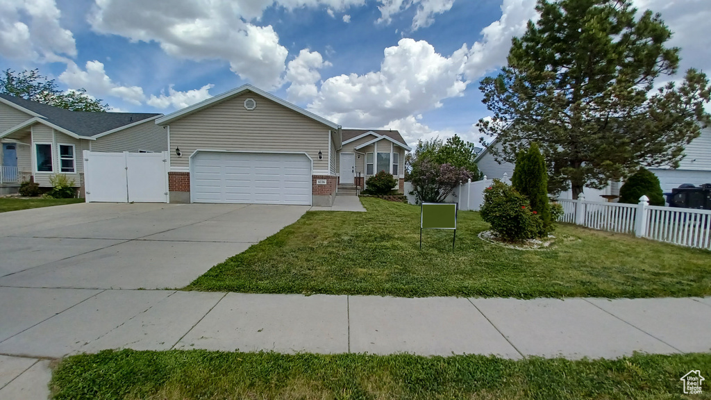 Ranch-style house featuring an attached garage, brick siding, concrete driveway, and a gate