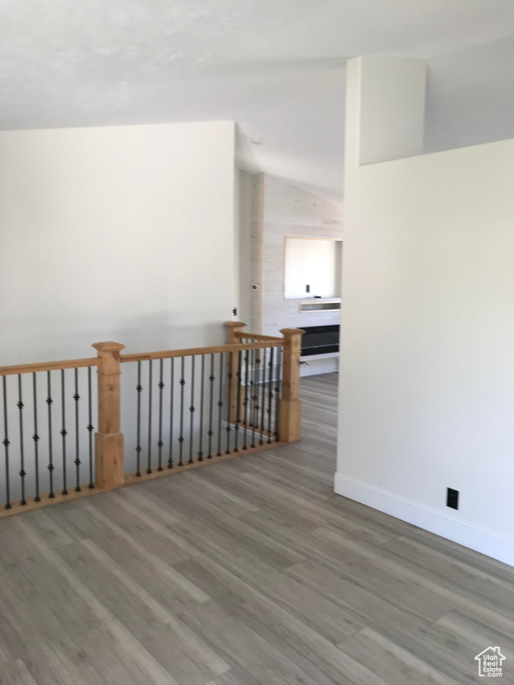Empty room with wood finished floors, vaulted ceiling, and baseboards