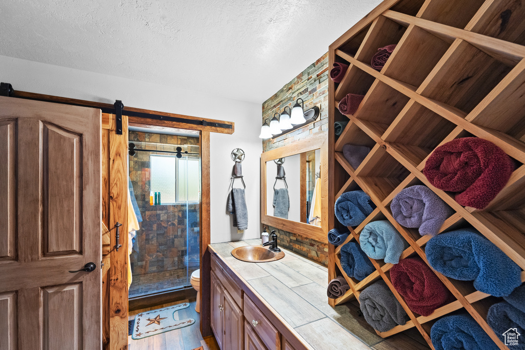 Bathroom featuring a shower stall, vanity, a textured ceiling, toilet, and wood finished floors