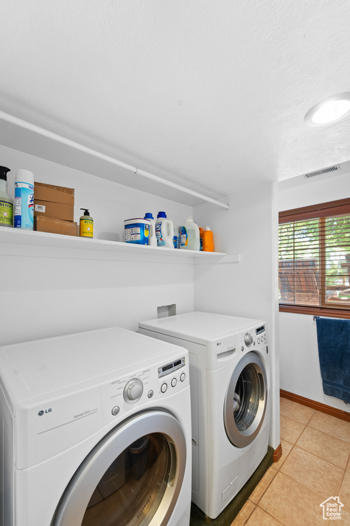 Laundry room with separate washer and dryer, light tile patterned floors, and baseboards