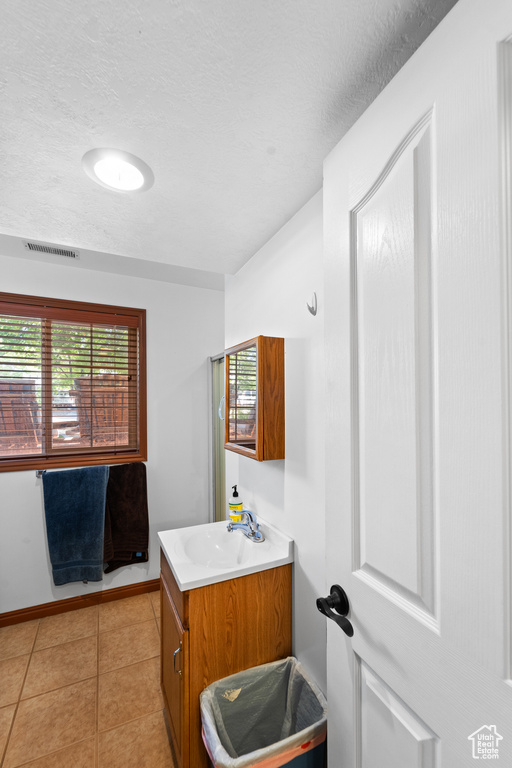 Bathroom featuring vanity, a textured ceiling, tile patterned floors, and baseboards