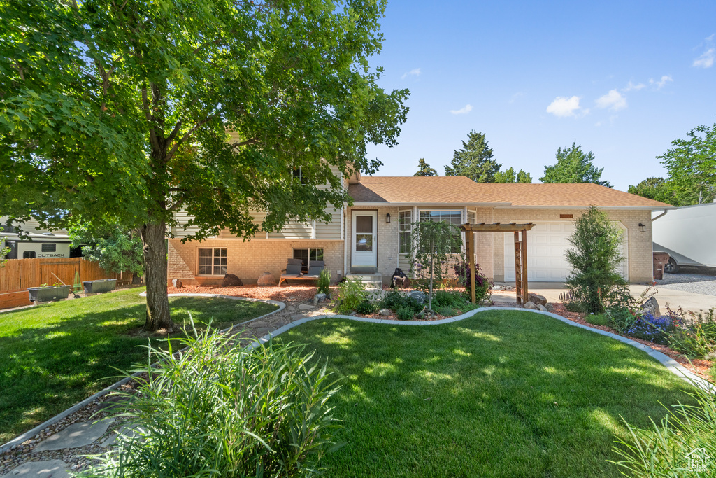 Split level home featuring brick siding, an attached garage, and concrete driveway