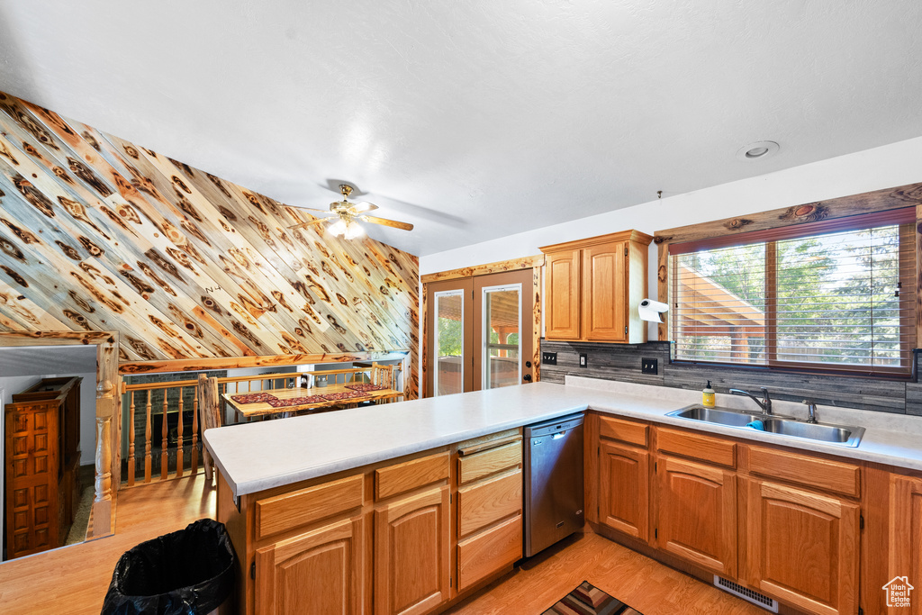 Kitchen featuring a sink, dishwasher, a peninsula, and light countertops