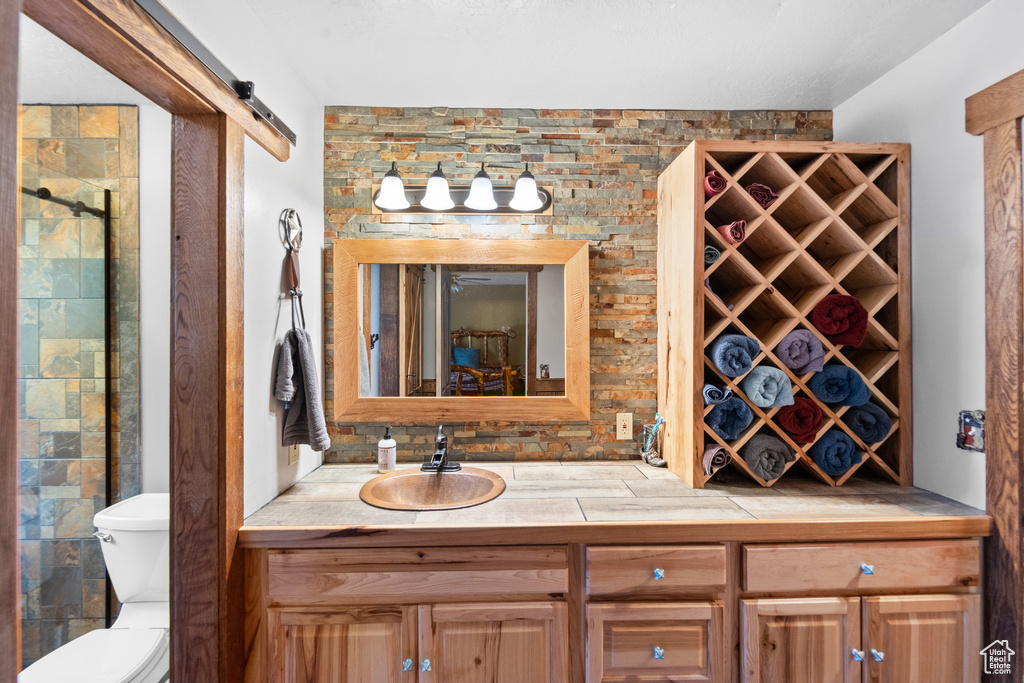 Full bathroom featuring toilet, vanity, and tiled shower