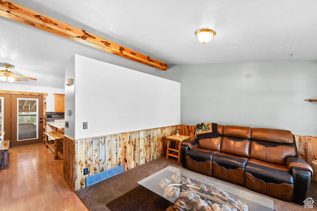 Living area featuring a wainscoted wall, wood walls, light wood-type flooring, and a ceiling fan
