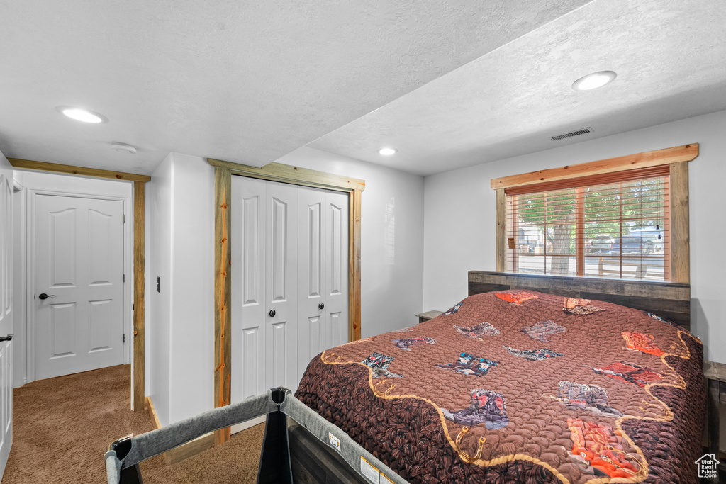 Carpeted bedroom with recessed lighting, a closet, a textured ceiling, and baseboards