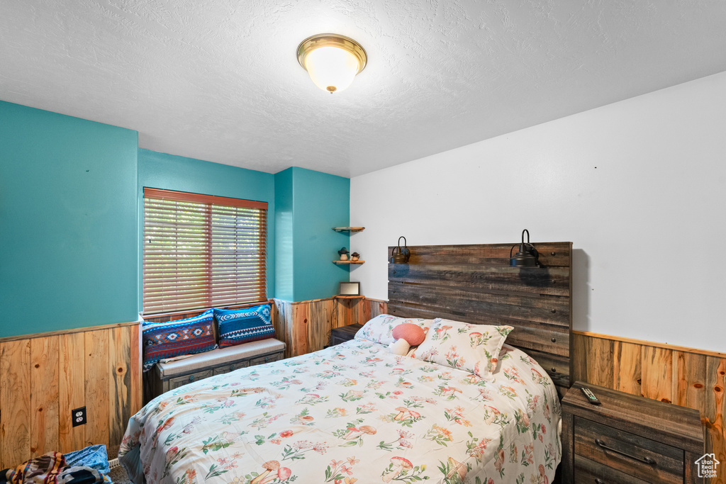Bedroom featuring a wainscoted wall and wooden walls