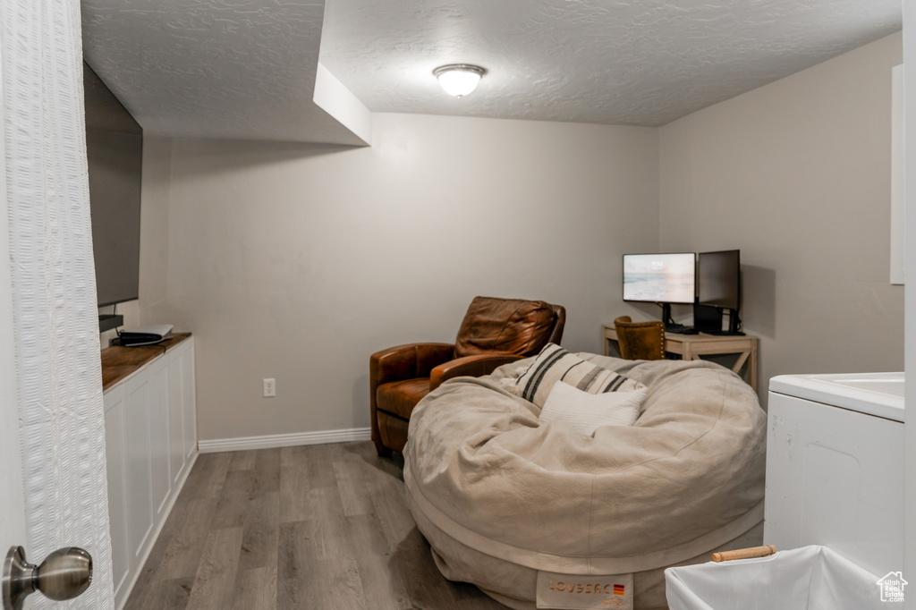 Sitting room with baseboards, a textured ceiling, and wood finished floors