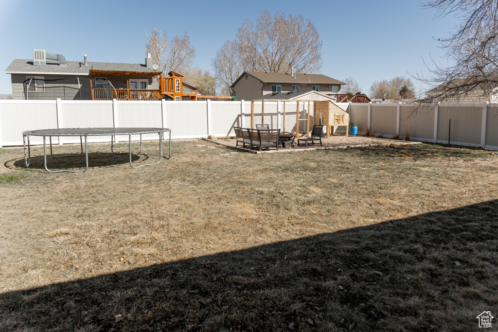 View of yard featuring a fenced backyard, a fire pit, and a trampoline