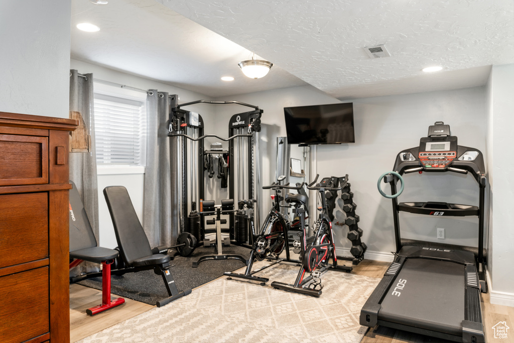 Exercise area with recessed lighting, baseboards, a textured ceiling, visible vents, and wood finished floors