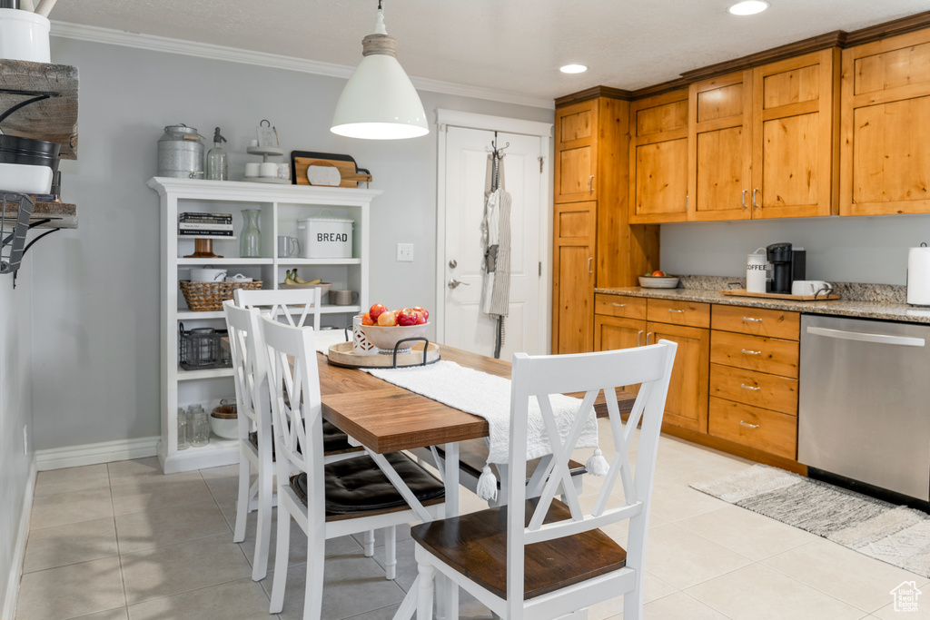 Kitchen with light tile patterned flooring, ornamental molding, light stone countertops, and stainless steel dishwasher