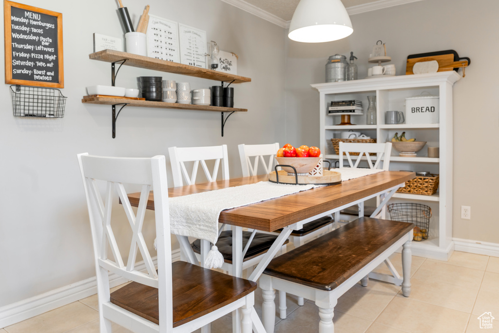 Tiled dining area featuring baseboards and crown molding
